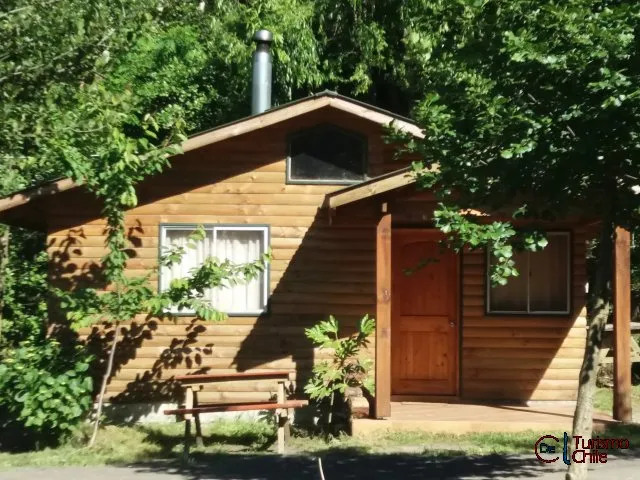 Cabaña de madera con chimenea y banca exterior en Cabañas Rucalhue