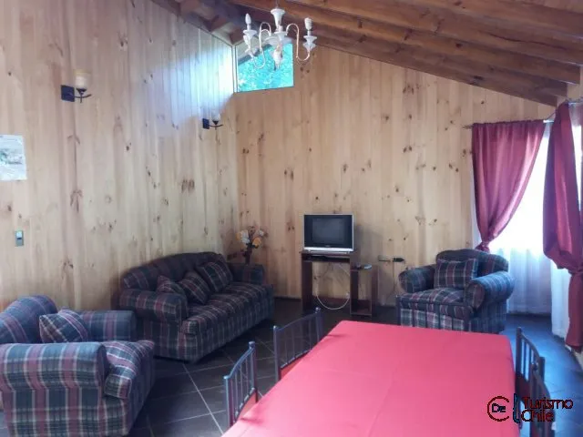 Amplio living con sofás de cuadros, chandelier y cortinas rojas en cabaña Rucalhue