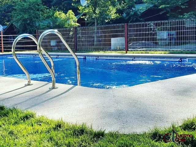 Piscina diurna con pasamanos de acero y jardín en Cabañas Rucalhue